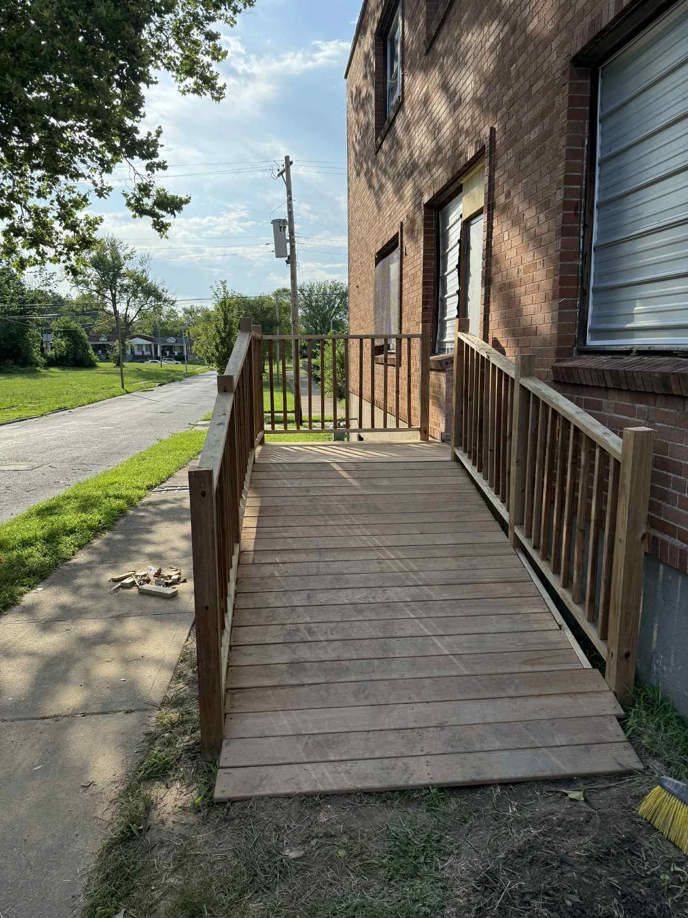 Newly built wood access ramp and deck beside a brick home