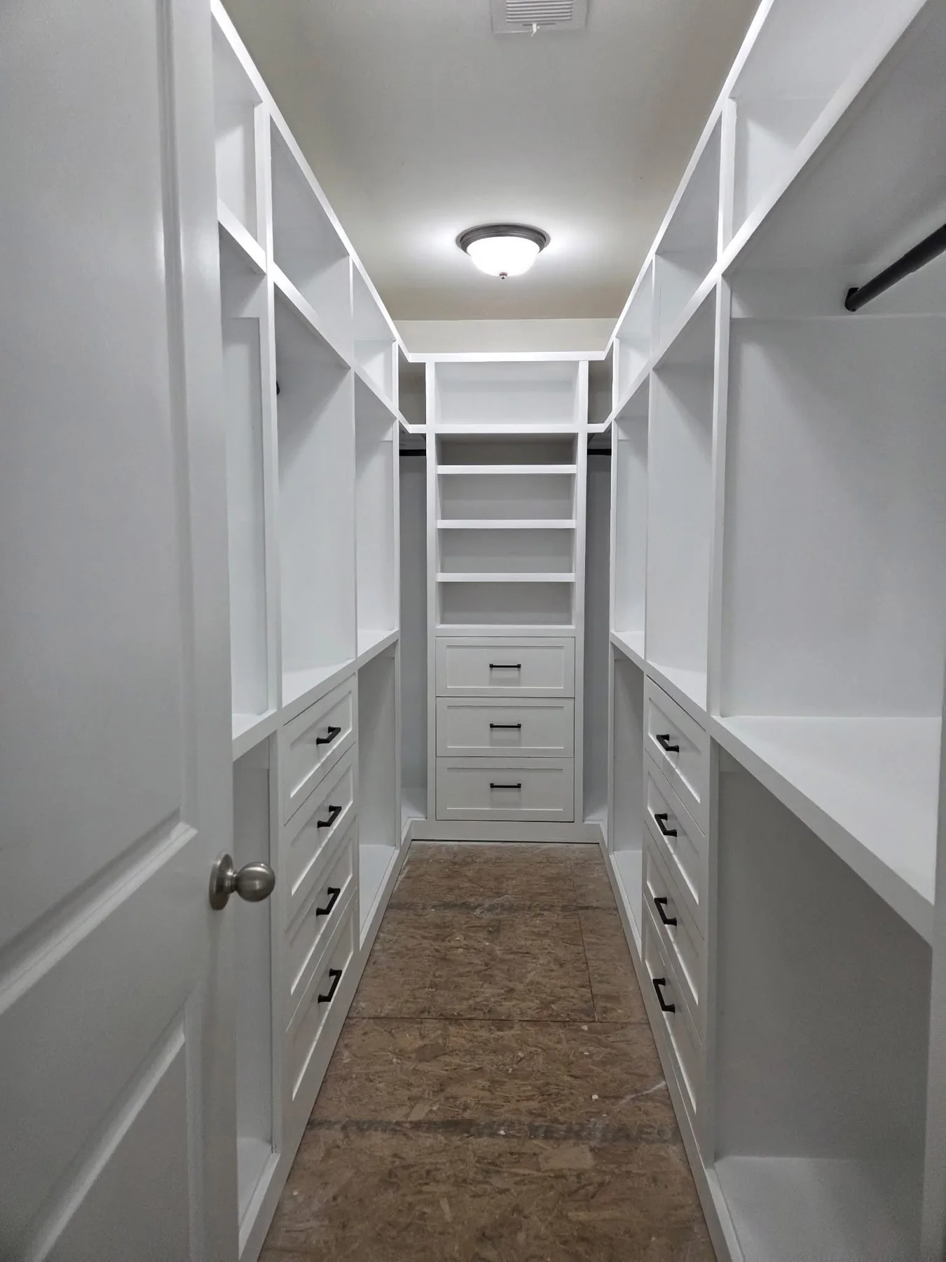 Fitted walk-in closet with floor-to-ceiling open shelving, clothes rails on both walls, built-in drawers, and a runner rug
